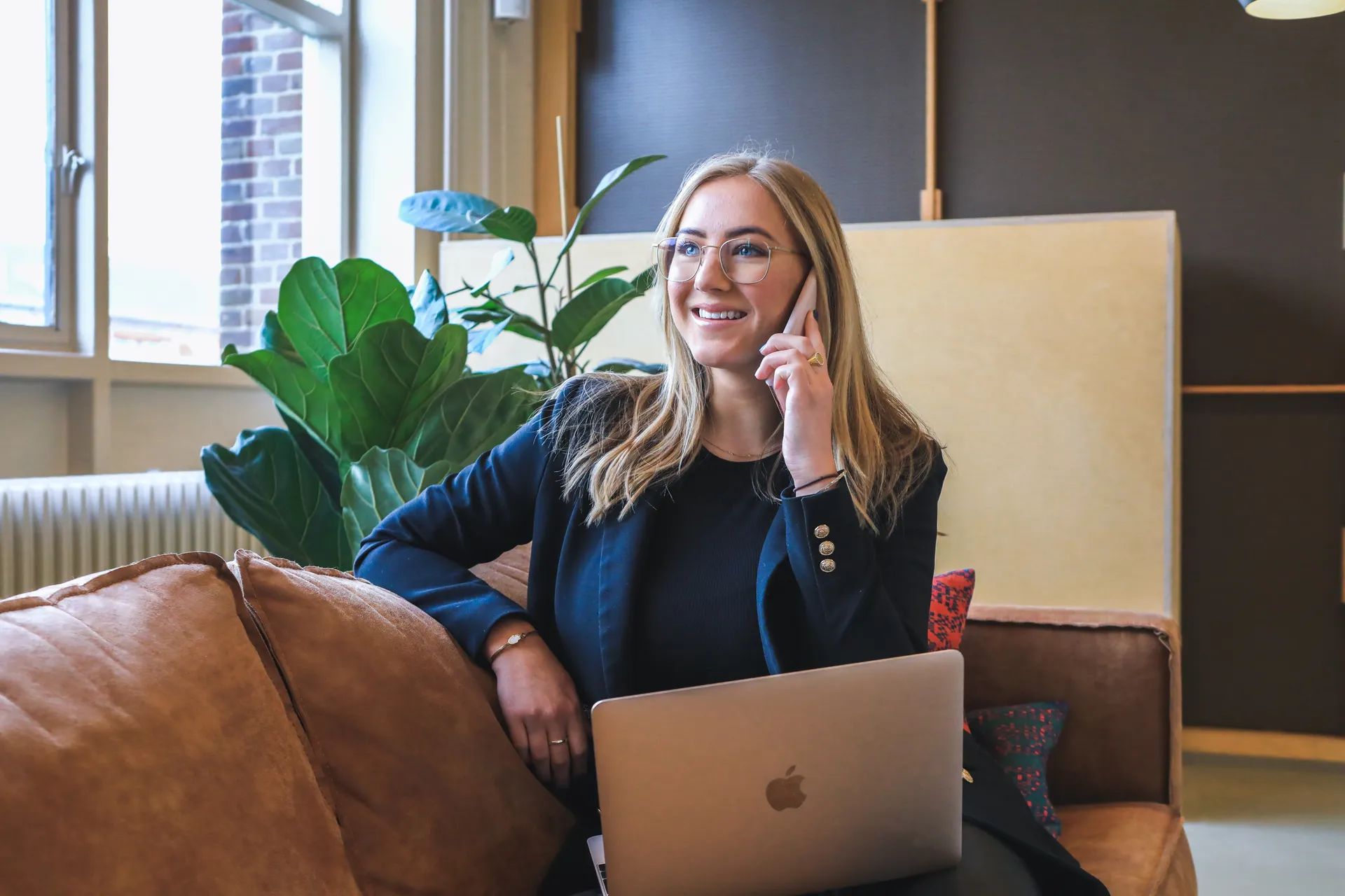 Kvinna med glasögon sitter i soffa och pratar med Lånekoll